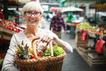 Wall Mural - Senior woman buying vegetables at the green market.