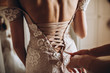 on the girl's white wedding dress, the bridesmaid tightens the ribbon on the corset of the dress
