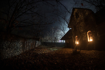 Wall Mural - old house with a ghost in the forest at night or abandoned haunted horror house in fog. old mystic b