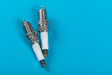 A set of new spark plugs a blue background.