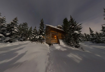 Wall Mural - Panorama house chalet during a snowfall in the trees winter forest at night in the moonlight