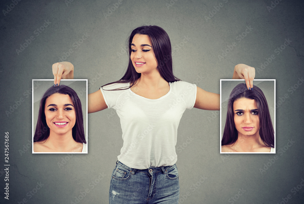 woman holding pictures with good and bad emotions having mood swings and smiling at positive herself - obrazy, fototapety, plakaty 