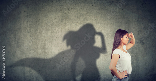Cuadros en Lienzo Side view of a woman imagining to be a super hero looking aspired