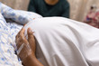 © Inez - An image of a pregnant lady lying in a hospital bed holding her tummy while she waits for her cesarean section.