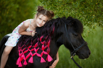 Cute little girl with black pony in the park