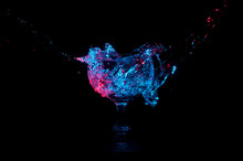 Blue And Red Water Splashing Into A Glass Chalice On A Black Background
