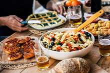 Close Up Of Dish Full Of Italian Pasta And Mixed Food For ñunch Or Dinner Time In Friendship For Group Of People Have Fun And Enjoy To Stay Together - Celebration And Event - Wooden Table And Colors