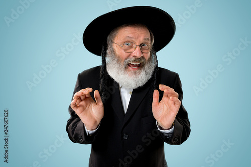 Cuadros en Lienzo Portrait of old senior orthodox Hasdim Jewish man with wooden Grager Ratchet at Jewish festival of Purim at studio