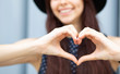 Closeup shot of cheerful girl with long hair making heart shape with her fingers. Space for text