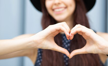 Closeup Shot Of Cheerful Girl With Long Hair Making Heart Shape With Her Fingers. Space For Text