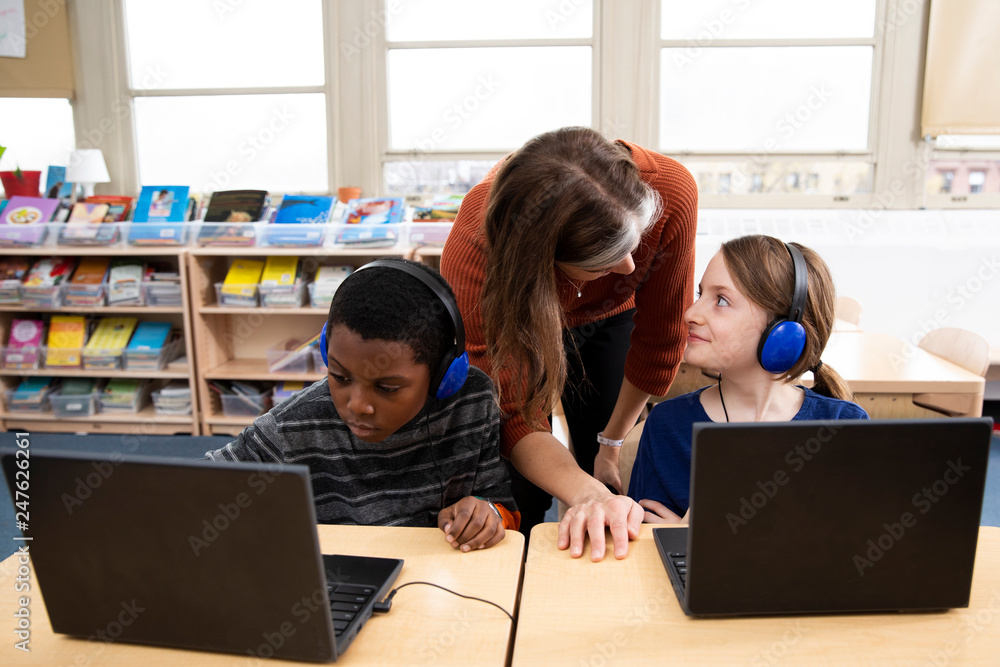 Teacher helping students with laptop computers Stock Photo | Adobe Stock