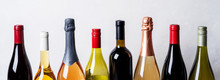 Tops From Different Kinds New Bottles Of Champagne, White, Red Wine On Light Background