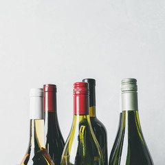 Wall Mural - Tops from different new bottles of champagne, white, red wine on light background