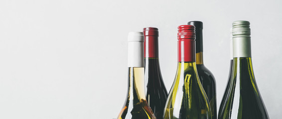 Wall Mural - Tops from different new bottles of champagne, white, red wine on light background