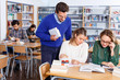 © JackF - Male teacher working with young female students in university library