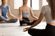 © fizkes - Female yoga teacher meditate with students in lotus position