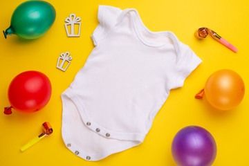 mockup Flat Lay white children shirt with toys and balls on a yellow background. Layout for the design and placement of logos, advertising, children's party baby shower, children's birthday