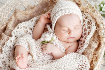 sweet newborn baby sleeps in a basket. beautiful newborn boy with flowers