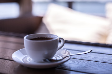 A small white porcelain espresso cup on a saucer with a teaspoon and two pieces of sugar