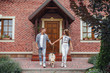 © Тарас Нагирняк - Portrait of excited couple standing outside new home with dog. Happy smiling family with labrador in front of the house.