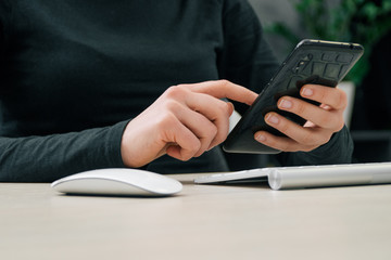 the woman hands holding the smart mobile phone with the keyboard and mouse 