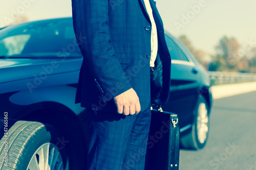 Fotomural .a businessman standing near in front of.luxury car holding brief case or diplom