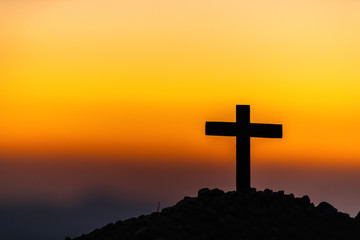 Wall Mural - The silhouette of the cross across the mountain at sunset