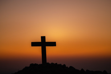 Wall Mural - The silhouette of the cross across the mountain at sunset