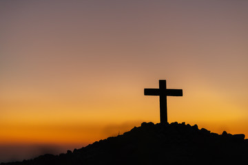 Wall Mural - The silhouette of the cross across the mountain at sunset