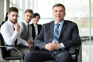 Sticker - Mature smiling business manager in front of his business team