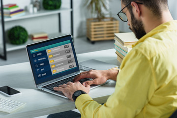 bearded man looking at laptop with sport bets website on screen in modern office
