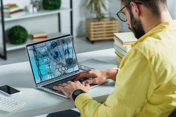 bearded man looking at laptop with medical website on screen in modern office