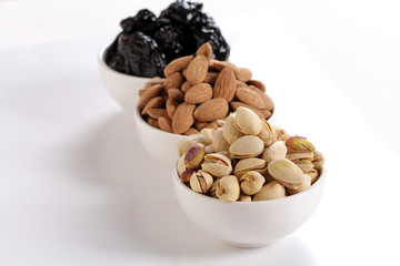 Wall Mural - Assorted nuts on white, dry fruits, mix nuts, roasted almond, prunes, pistachio