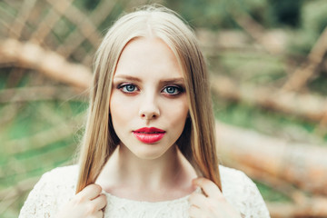 Close up natural portrait of young happy cute cheerful caucasian beautiful girl witn long natural blondie hair walking in park in summer evening