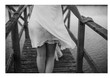 Chica andando por un puente de madera sobre el mar en blanco y negro