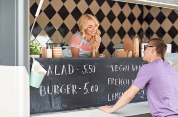 Poster - street sale and people concept - happy young saleswoman at food truck serving male customer