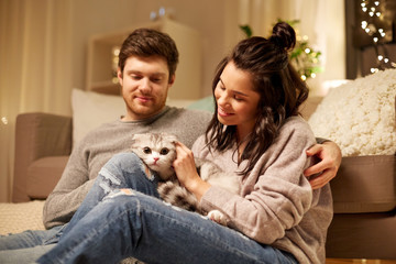 Wall Mural - pets, hygge and people concept - happy couple with cat at home