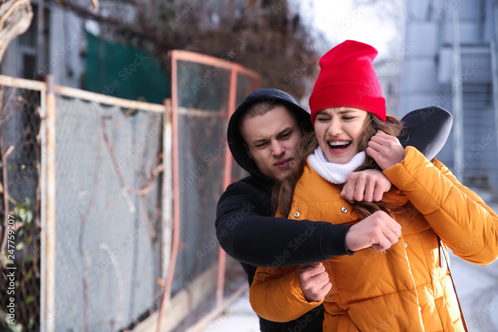 Young woman defending herself from thief outdoors