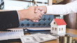 © Ngampol - Image of successful deal of real estate, Broker and client shaking hands after signing contract approved application form, concerning mortgage loan offer for and house insurance