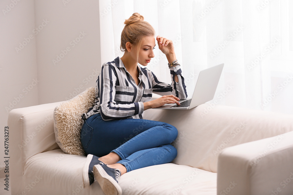 Beautiful young woman using laptop at home