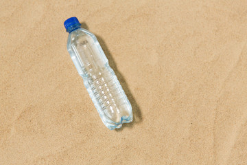 hydration and summer concept - bottle of water on beach sand