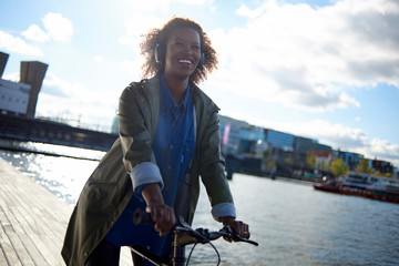 Wall Mural - Beautiful black woman wearing headphones in urban city setting during sunrise