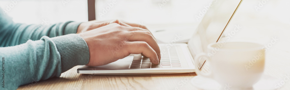 cropped view of man typing on laptop while working at home - obrazy, fototapety, plakaty 