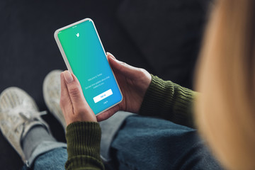 selective focus of woman holding smartphone with twitter app on screen