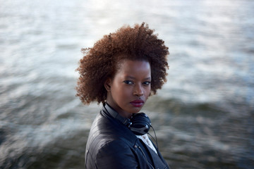 Wall Mural - Beautiful black woman wearing headphones in urban city setting during sunrise