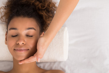 Wall Mural - African-american woman getting face massage at beauty salon