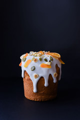 Easter, Easter cake on a dark background with a complex composition, beautiful scenery, dried fruits, movement, hands. Traditional Kulich, Paska Easter Bread.