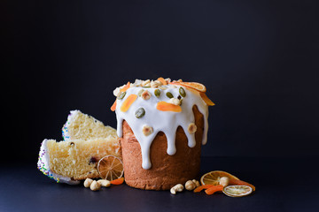 Easter, Easter cake on a dark background with a complex composition, beautiful scenery, dried fruits, movement, hands. Traditional Kulich, Paska Easter Bread.