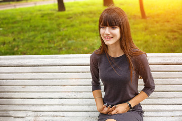 Wall Mural - young woman in the Park sitting on a bench happy smile, the concept of relaxation and happy mood