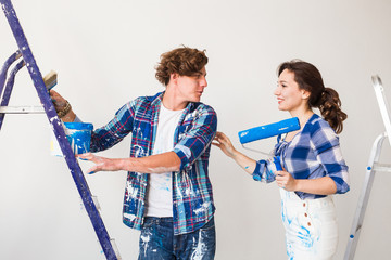 Repair, renovation and love couple concept - young family doing redecoration and painting walls together and laughing.